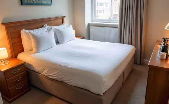 A well-organized guest room with a comfortable air mattress made up with fresh linens and fluffy pillows, a small night lamp on the bedside table, and a stock of essential toiletries neatly arranged on the dresser