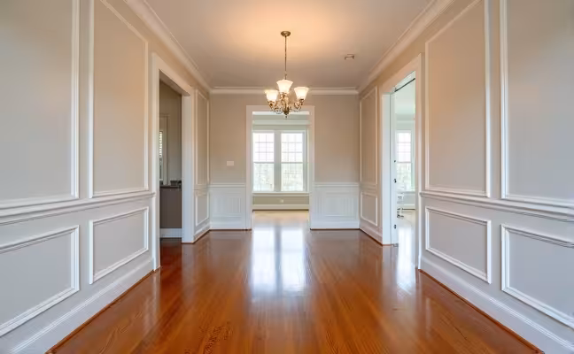 A spacious dining room adorned with classic wainscoting, adding texture, depth and an upscale touch to the walls, contrasted with a gleaming hardwood floor